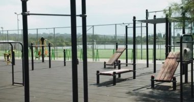 Güneşli yaz gününde şehir parkındaki spor sahasında spor yapmak için yatay barlara ve modern egzersiz ekipmanlarına bakın. Yatay çubuklu spor sahası ve diğer yeni egzersiz ekipmanları