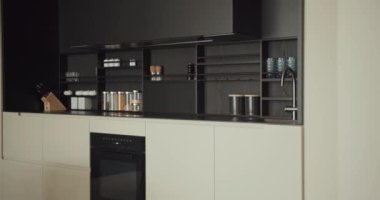 Gösterişli modern mutfak, siyah raflar, beyaz dolaplar ve paslanmaz çelik eşyalar. Minimalist bir görünüş için mükemmel organize edilmiş. Temiz Tasarım ve Siyah Aksanlı Modern Mutfak