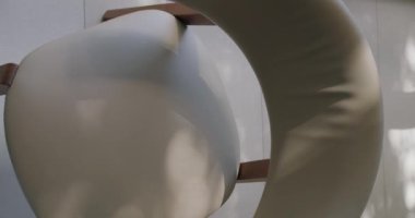 Gölgeler ve ışığa odaklanan gri tonda modern bir sandalyenin sanatsal görüşü. Soyut ve minimalist tasarım elementleri vurgulanarak sakin ve düşünceli bir atmosfer yaratılır. Dikey video.