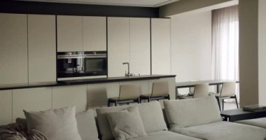 İyi tasarlanmış, rahat bir yaşam alanına entegre edilmiş, gösterişli dolaplar ve yumuşak renk paletiyle donatılmış modern bir mutfak. Şık Modern Mutfak ve Şık Ev Dekorasyonunda Yaşam Alanı