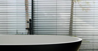 Modern bir masa ve yatay güneşliklerle kaplı geniş pencereli şık ve çağdaş bir ofis alanı. İş için ideal. Perdeler Arasında Görünümü Olan Modern Banyo İçi