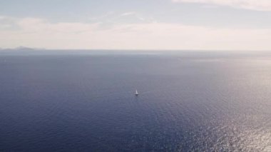 Derin mavi sulardaki beyaz teknenin görüntüsü. Yat gezintisi yapan zengin yatın yukarıdan görünüşü. Lüks gemiyle yaz seyahati. Lüks yelkenli. Yaz lüks modern tekne gezisi. Lüks gemi seyahati.