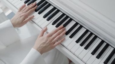 Beyaz bir ortamda piyano çalan ellerin yakın plan görüntüsü. Huzurlu ve zarif bir ortamda müzikal performans, beceri ve pratiği temsil eder. Serene Space 'de Piyano Çalan Eller Kapanışı