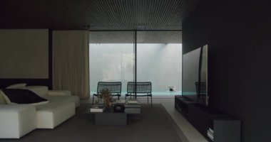 Modern oturma odasında sofistike beyaz koltuklar, düz ekran televizyon, sessiz tonlar ve açık havuz manzarası var. Zarif Modern Oturma Odası Şık Mobilyaları ve Geniş Pencereleri