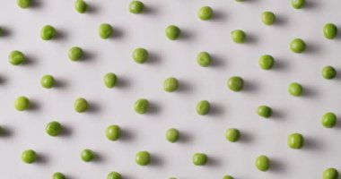 Fresh green peas placed side by side rotate on a white platform. Raw green peas in motion on isolated white background rotating with same motion.