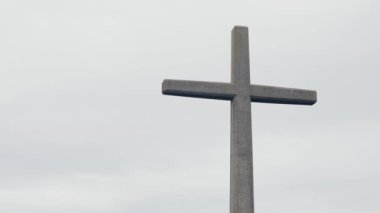 Portekiz 'de bulutlu bir gökyüzüne karşı büyük bir taş haç dik duruyor. İnancı ve ruhaniliği simgeliyor. Gri Gök 'e Karşı Taş Haç İnancı ve Dini simgeliyor