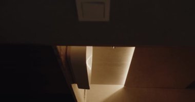 Modern bir mutfak çekmecesinin yakın plan görüntüsü. Hafif açık, yumuşak ve sıcak ışıklandırmayla vurgulanmış, rahat bir atmosfer yaratıyor. Bu resim, minimalist iç tasarımı sergiliyor. Dikey video.