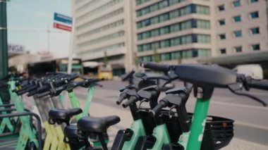 Lizbon, Portekiz 'de arka planda otobüsü olan bir sıra yeşil elektrikli scooter. Şehir ulaşımı ve çevre dostu seyahat kavramı. Yeşil Elektrikli Scooter ve Bisikletler Park Edildi