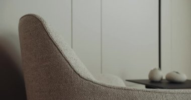 Bu resim, nötr renk paleti ile minimalist bir ortamda desenli bir sandalyeyi vurgulayan modern ve şık bir yaşam alanı sergiliyor. Minimalist İç Tasarım Yönetmeni: Modern Moda Koltuğu