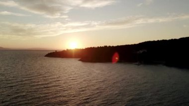 Denizden yükselen güneş. Renkli bulutlu gökyüzü ve güneş ışınları. Sakin denizin üzerinde gün doğumu. Güneş denizin tam üstünden doğar ve suyun yüzeyine büyük ve güzel bir ışık yansıtır..