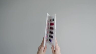 Tırnak cilası paletini farklı renklerde tutan bir el. Manikür, tırnak sanatı ve güzellik ilhamı için mükemmel. Renkli Tırnak Cilası Örnekleri