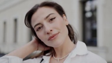 Kendine güvenen genç bir kadının yakın plan portresi. Nazik bir gülüşü var. Beyaz gömlek giymiş, kentli bir geçmişi var. Kentsel Ayarlama, Yakın Çekim Portresindeki Kendine Güvenen Genç Kadın