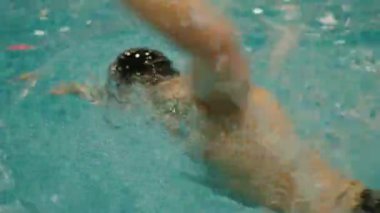 Canlı bir turkuaz havuzda yüzen bir yüzücünün dinamik görüntüsü, güç ve su dokusunu gösteriyor. Bir Havuzda Yüzücü, Suyun Dinamik Hareketini Yakalıyor