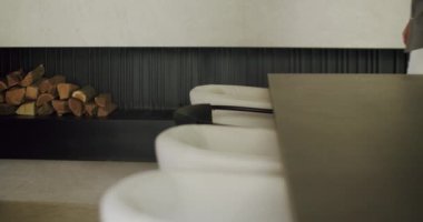 Lüks bir oturma odası, parlak siyah bir odun yığını özelliği ve çağdaş bir ev ortamında gelişigüzel yürüyen bir kişi. Modern Oturma Odası