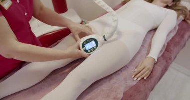 Profesyonel bir terapist, lenfatik drenaj terapisi için modern bir cihaz kullanır. Müşteri, iyi donanımlı bir kaplıcada mayo giyer. Spa Ayarlarında Profesyonel Lenfatik Drenaj Terapisi