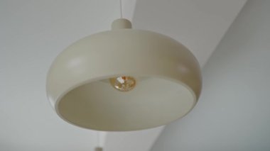 Modern krem rengi kolye ışığının yakın çekimi. İçi temiz bir şekilde aydınlatılmış bir ampul. Moda Krem Abajurlu Modern İç Kolye Işığı. Modern Krem Lambası