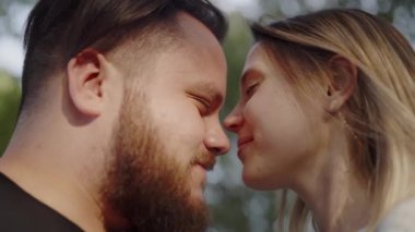 Öpüşmek üzere olan genç bir çiftin güzel bir günbatımında şefkatli ve sevgi dolu bir anı sergilerken yakın çekimi. Romantik Günbatımının tadını çıkaran bir çift arasındaki mahrem an