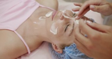 Profesyonel bir cilt bakımının yakından görüntüsü, bir uzmanın bir kadının yüzüne yüz maskesi taktığı, rahatlamayı ve deri sağlığını teşvik ettiği. Profesyonel Cilt Tedavisi, Yüz maskesi