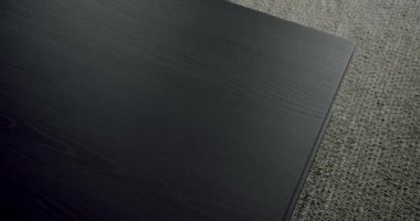 Koyu renkli, ahşap bir masa yüzeyinin yakın plan çekimi görünür bir tahılla, zıt desenli bir halı zeminine göre ayarlanmış. Halıdaki Koyu Dokulu Ahşap Masa 'nın Yakın Görüntüsü