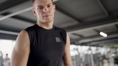 Genç bir atletik adam iyi donanımlı bir spor salonunda antrenmanına odaklanmış, azim ve fitness hedefleri gösteriyor. Modern Spor Ortamında Odaklanmış Genç Adam Eğitimi