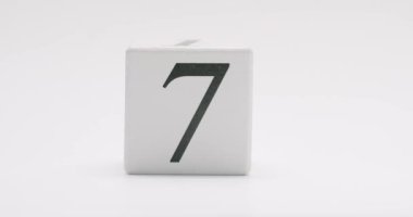 Beyaz arka planda yedi numaralı tahta bloğun yer aldığı minimalist bir fotoğraf. Sayma, tarih ya da şanslı sayı 7 'yi içeren kavramlar için mükemmel.