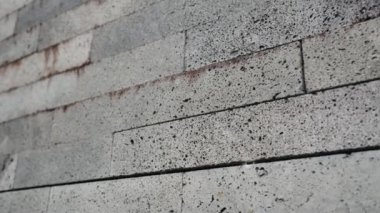 Pas lekeli Gri Beton Duvar Tuğlalarının yakın çekimi. Görünür dokuları ve pas lekeleri olan gri beton duvarın detaylı yakın çekimi, endüstriyel ve kentsel elementleri gösteriyor..