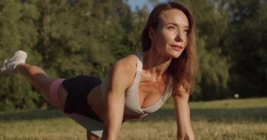 Spor eğitmeni eğitimi, direnç bandı, lastik kayışla bacak egzersizi yapan bir kadın. Selülit için geri tepmeli kalça kası aktivasyonu. Selülit için geri tepmeli kalça kası etkinleştirmesi