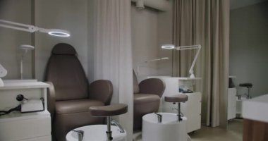 Gösterişli sandalyeler, parlak iş aydınlatmaları ve temiz çalışma yerlerinin olduğu profesyonel bir manikür salonu. Güzellik tedavileri için mükemmel. Konforlu Tasarım Koltuklarıyla Modern Manikür Salonu