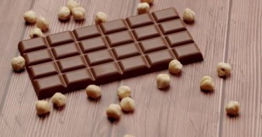 Tahta bir yüzeyde fındıkla çevrili lezzetli bir sütlü çikolata. Zengin, kremalı çikolata aromalı, fındık ezmesiyle birleşmiş lezzetli bir ziyafet..