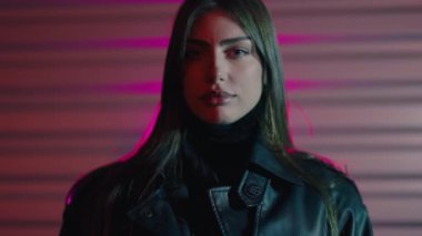 Deri ceketli kadın. Şık bir kız. Profesyonel mankenin yüzü. Genç, lüks, seksi bir kadın gece vakti renkli bir arka planda kameraya bakıyor..