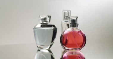 Ayna yüzeyinde sergilenen zarif parfüm şişelerinin bir koleksiyonu büyüleyici yansımalar yaratıyor. Şişelerin çeşitli şekilleri ve renkleri lüks ve sofistike bir hissi çağrıştırıyor..