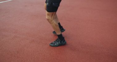 Atletik vücutlu genç bir adam koşuyor ve dışarıda yoğun bir idmandan önce ısınıyor. Çapraz eğitim konsepti. Atletik adam stadyumda dizlerinin üzerinde koşuyor. Koşuyorum..