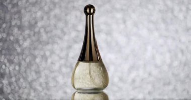 Parlak metalik kaplamalı zarif cam parfüm şişesi ışıldayan bir bokeh arka planına dayanıyor. Lüks güzellik ve parfüm reklamları için mükemmel. Zarif Parfüm Şişe