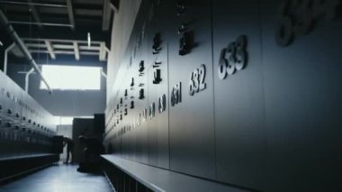 Dolapları numaralandırılmış ve arka planda hazırlanan insanlar olan çağdaş spor salonu. Zindelik ve sağlık kavramları için temiz ve asgari çevre ideal. Numaralı Dolaplar