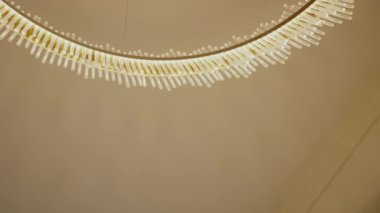 Minimalist bej arkaplan, minimalist tasarım ve çağdaş zarafeti gösteren modern dairesel bir LED avizenin yakın çekim görüntüsü. Modern Dairesel LED Avize