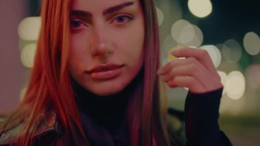 Gece lambalarının arka planında genç bir kadının portresi. Dışarısı, güzellik, akşam, yaşam tarzı, model pozu şehir caddesi. Geceleri şehir merkezinde poz veren güzel bir kadın..
