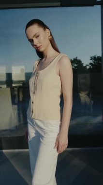 Kendine güvenen genç bir kadın dışarıda poz veriyor. Doğal güneş ışığı altında şık moda kıyafetleri sergiliyor. Moda, özgüven ve modern tarz için ideal. Açık havada poz veren zarif genç kadın.
