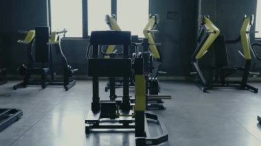 Çağdaş bir spor salonu, çeşitli egzersiz makineleri, iyi ışıklandırılmış bir alanda güçlü eğitim ekipmanlarını ön plana çıkarıyor. Modern Jimnastik İçi Güç ve Zindelik Eğitimi İçin Ekipman