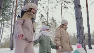 Neşeli bir aile karlı bir ormanda yürüyor, kışın çocuklarıyla birlikte bir annenin mutluluğunu yakalıyorlar. Aile Karlı Ormanda Birlikte Kış Yürüyüşü Yapıyor