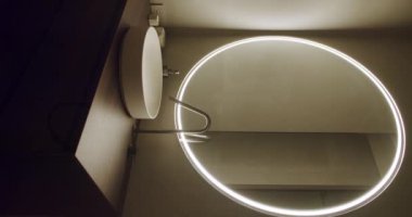Yuvarlak LED ışıklı ayna, parlak beyaz lavabo ve şık ahşap tezgahlı zarif modern banyo. İç tasarım ve mimari kavramlar için ideal. Banyo İçi Dikey