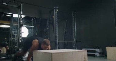 Odaklanmış bir sporcu, iyi donanımlı, çağdaş bir spor salonunda, dayanıklılık ve güç gösterisi yaparak yorucu bir egzersiz yapıyor. Genç Adam Modern Spor Salonu 'nda Sıkı Çalışıyor