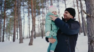 Karlı bir ormanda genç kızını kaldıran bir babanın iç açıcı kış sahnesi. Hem gülerek hem de dışarıda soğuk bir günün tadını çıkararak. Karlı bir kış ormanında Kızını Tutan Baba