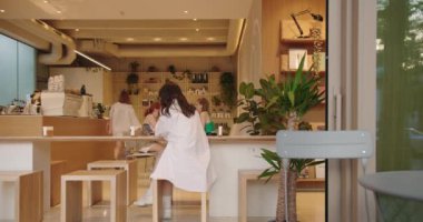 Modern kafe, şık, minimalist tasarım işyerinde baristaları ve ambiyansı seven müşterileri barındırıyor. Ahşap döşemeler ve bitkiler sıcacık, taze bir his katar..