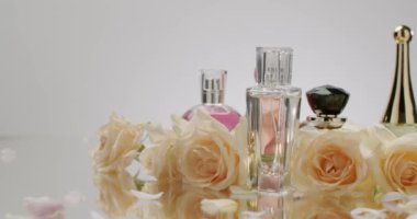 Güzel güllerle çevrili zarif parfüm şişeleri lüks ve sofistike bir koku deneyimi yaratıyor. Güzellik ve yaşam tarzı temaları için mükemmel. Zarif parfüm şişeleri