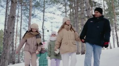 Beş kişilik mutlu bir ailenin karlı bir çam ormanında birlikte yürüdüğü resmedilmiştir. Gülümsemeler ve kış giysileri soğukta neşeli bir günü vurgular. Neşeli Aile Karlı Ormanda Kış Yürüyüşü Yapıyor