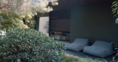 Terası ve bahçesi olan modern bir tatil evi. Arka bahçedeki verandada, kır evinin yanında modern tasarımı olan rahat fasulye koltukları. Tranquil Garden 'daki Modern Açık Salon Bölgesi