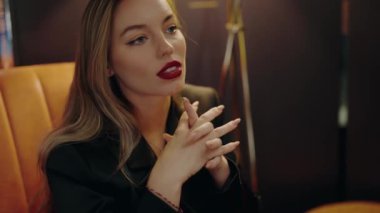Kırmızı rujlu düşünceli bir kadının portresi. Kapalı bir odada oturuyor. Zarafet ve tefekkür yayarak sofistike ve yansıtıcı bir ruh hali yaratıyor. Genç Güzel Kadın.