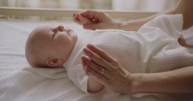 Neşeli anne yeni doğmuş bebeğiyle oynuyor, şefkatle küçük ellerini tutuyor ve komik bir şarkı söylüyor. İletişim kurun. Mutlu annelik ve aile kavramı. Çocuk kavramı, bebek, ebeveynlik.