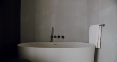 Zarif, beyaz, serbest banyo küveti ve düzgün asılı havluyla modern minimalist bir banyo. Huzur ve incelik hissi uyandırıyor. Minimalist Modern Banyo, Serbest Küvet
