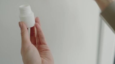 Beyaz bir şişeden hap alan, sağlık, ilaç ve sağlık kavramlarını vurgulayan bir elin yakın plan görüntüsü. Tıbbi ve ilaç kullanımları için idealdir. El Bir Hap Alırken